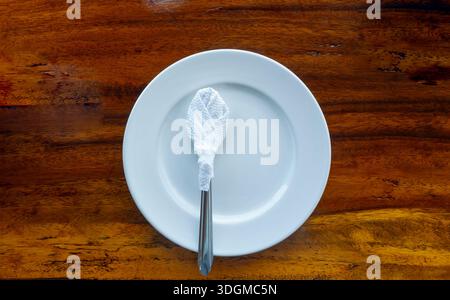 Top view of white plate with teaspoon is on brown wooden table. Stock Photo