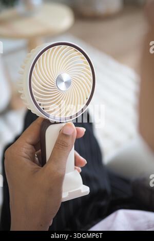 Hand held fan is used indoors on a warm day Stock Photo