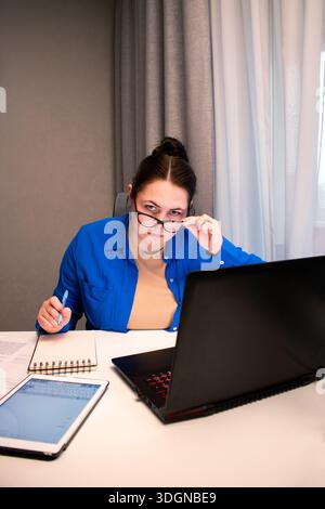 Remote employee analyzing reports during productive workday at home office. Reviewing charts and data on laptop screen during focused work hours. Corp Stock Photo