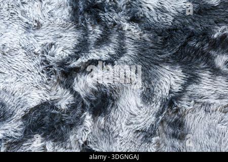 Detailed closeup view of luxurious soft grey faux fur texture background with swirls of white and black hair creating comfortable warm fuzzy plush rug Stock Photo