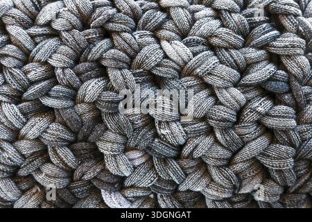 Detailed full frame close up grey knitted woolen pattern background texture showing cozy handmade craft with rough interlocking yarn loops and warm wo Stock Photo