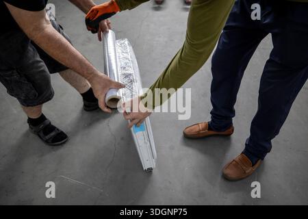 Production area for metal-plastic or PVC windows, commonly known as vinyl window. Two workers packaging a plastic window, securing the protective wrap Stock Photo