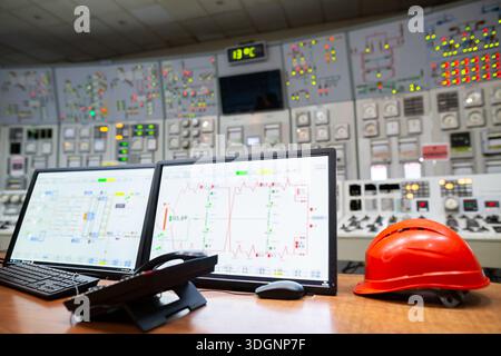 Control room for monitoring and managing industrial operations, with various control panels, analog and digital displays, buttons, and switches. A com Stock Photo