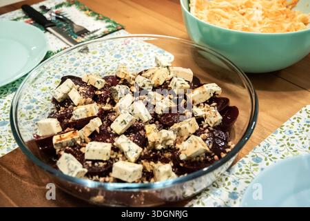 Close-up of beetroot salad topped with blue cheese and walnuts, served in glass bowl on dining table. Stock Photo