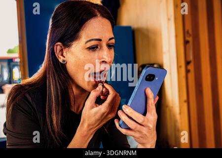 Woman applying lipstick using smartphone as mirror Stock Photo