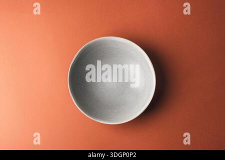 Grey plate on warm brown background. Top view, flat lay. Stock Photo