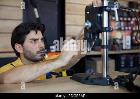 A male worker is diligently working on a drilling machine Stock Photo