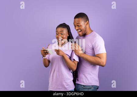 Portrait of surprised black couple using smartphone Stock Photo