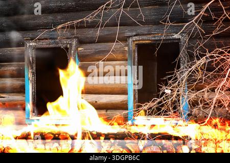 Wooden house after the fire. Coals on the logs. The ashes of the house from fire. Burnt destroyed cottage. Stock Photo