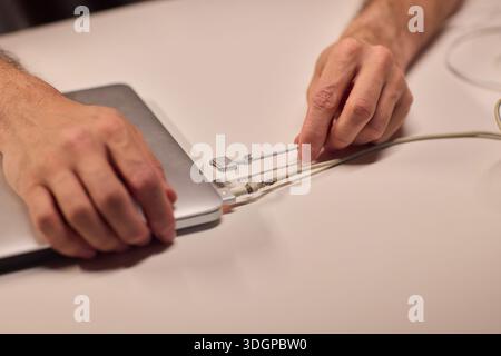 Repairing laptop power cord, Detailed image of fixing broken laptop charger wire, Closeup of skillful person restoring worn electrical cord for Stock Photo