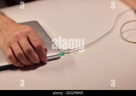 Repairing laptop power cord, Detailed image of fixing broken laptop charger wire, Closeup of skillful person restoring worn electrical cord for Stock Photo