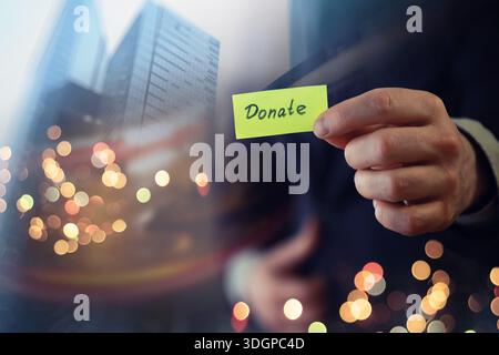 Businessman shows a wooden block with the word donate. Charitable donation in business concept. Stock Photo