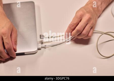 Repairing laptop power cord, Detailed image of fixing broken laptop charger wire, Closeup of skillful person restoring worn electrical cord for Stock Photo