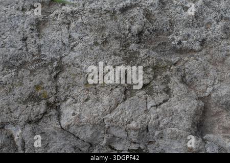 Weathered stone wall with rough cracked surface and natural gray rock texture, suitable for architectural and abstract backgrounds Stock Photo