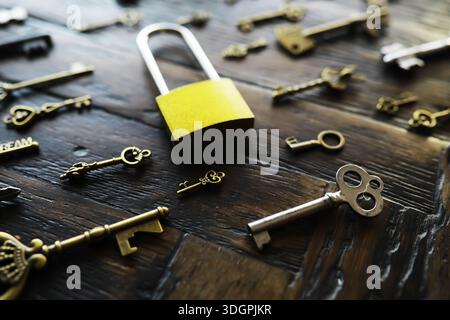 A lot of metal keys and a steel lock on a wooden boards. Vintage rusty padlock surrounded by old keys. Security or secret protection concept. Internet Stock Photo