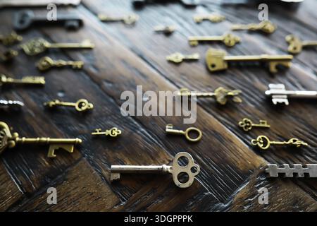 A lot of metal keys and a steel lock on a wooden boards. Vintage rusty padlock surrounded by old keys. Security or secret protection concept. Internet Stock Photo