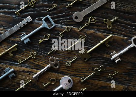 A lot of metal keys and a steel lock on a wooden boards. Vintage rusty padlock surrounded by old keys. Security or secret protection concept. Internet Stock Photo