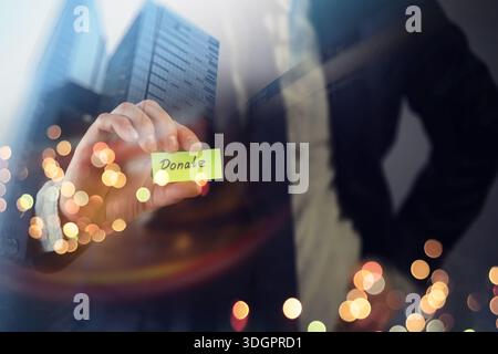 Businessman shows a wooden block with the word donate. Charitable donation in business concept. Stock Photo