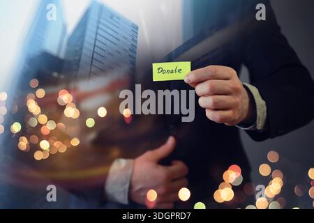 Businessman shows a wooden block with the word donate. Charitable donation in business concept. Stock Photo