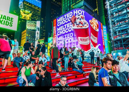 Beautiful night view of people resting on famous red staircase in Times Square surrounded by bright lights. New York. USA. Stock Photo