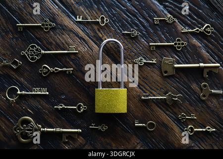 A lot of metal keys and a steel lock on a wooden boards. Vintage rusty padlock surrounded by old keys. Security or secret protection concept. Internet Stock Photo