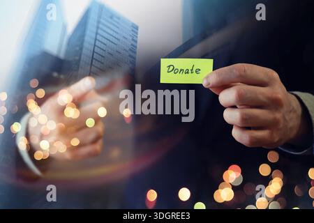 Businessman shows a wooden block with the word donate. Charitable donation in business concept. Stock Photo