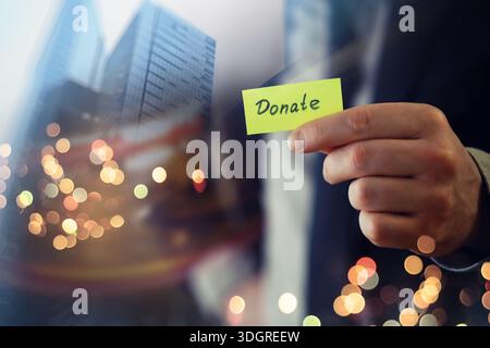Businessman shows a wooden block with the word donate. Charitable donation in business concept. Stock Photo