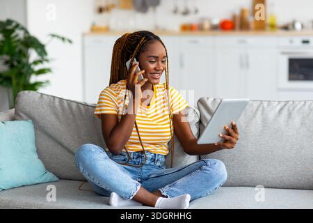 Afro american woman freelancer talking on phone and using tablet Stock Photo