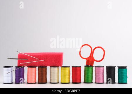 Spools of thread, scissors and needle on white background Stock Photo