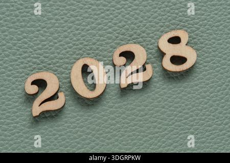 Wooden numbers 2028 on green leather texture background, business concept Stock Photo
