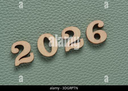 Wooden numbers 2026 on green leather texture background, business concept Stock Photo