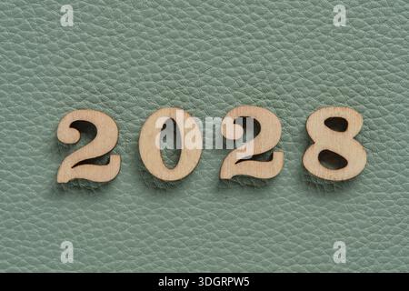 Wooden numbers 2028 on green leather texture background, business concept Stock Photo
