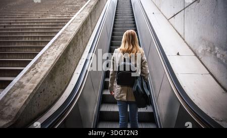 Businesswoman going up escalator in city subway. Woman commuter in urban environment on her way to work. City life Stock Photo