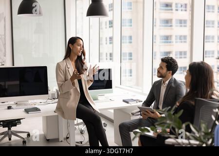 Confident female project manager discussing project plan with teammates Stock Photo