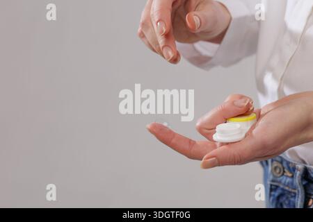 Hands presenting eyeglasses and contact lens case on blue studio background with copy space. Ideal for website banner about vision correction options Stock Photo