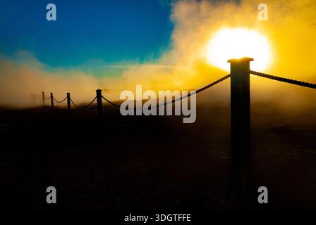 Steam and Sunlight Over Volcanic Ground with Fence Posts in Geothermal Landscape of Iceland Stock Photo