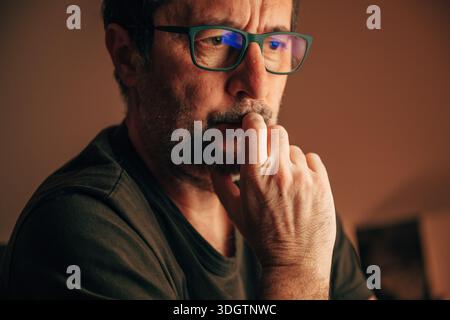 Serious concern, thoughtful middle-aged man with glasses hand on chin, selective focus Stock Photo