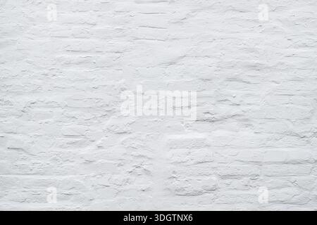 White painted brick wall texture with rough plaster and uneven mortar as background Stock Photo