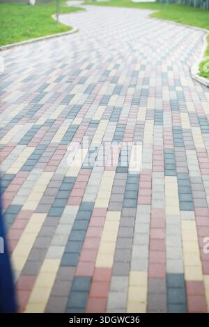 City street paved with three-color paving slabs. Sidewalk with gray, yellow and red cement rectangular tiles. Multi-colored paints of a modern city. S Stock Photo