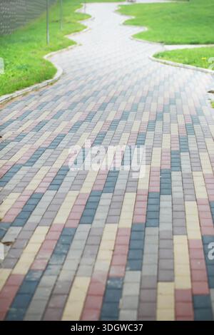 City street paved with three-color paving slabs. Sidewalk with gray, yellow and red cement rectangular tiles. Multi-colored paints of a modern city. S Stock Photo