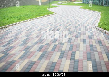 City street paved with three-color paving slabs. Sidewalk with gray, yellow and red cement rectangular tiles. Multi-colored paints of a modern city. S Stock Photo