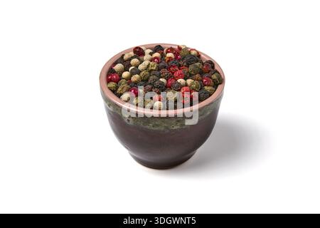 Multicolored peppercorns in a clay bowl isolated on white background. Stock Photo