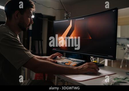 Male graphic designer working on computer screen displaying 3d rendering software, highlighting concepts of freelancing, professional remote work Stock Photo
