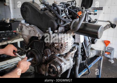 Auto mechanic hands adjusting car engine with wrench, performing repair and maintenance in vehicle service workshop Stock Photo