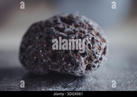 Close up of a dark, porous volcanic scoria rock showing vesicular texture Stock Photo