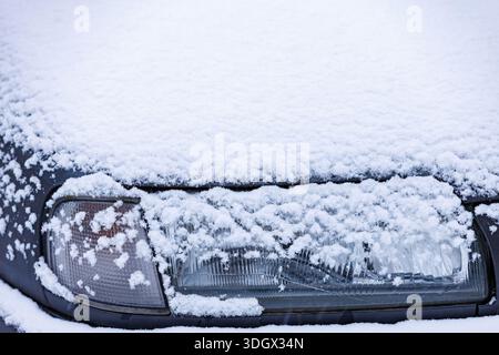 Car partially covered with fresh snow after winter snowfall. Cold
