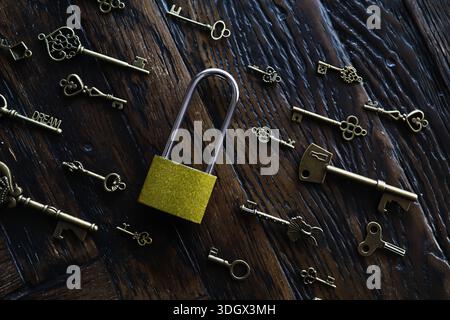 A lot of metal keys and a steel lock on a wooden boards. Vintage rusty padlock surrounded by old keys. Security or secret protection concept. Internet Stock Photo
