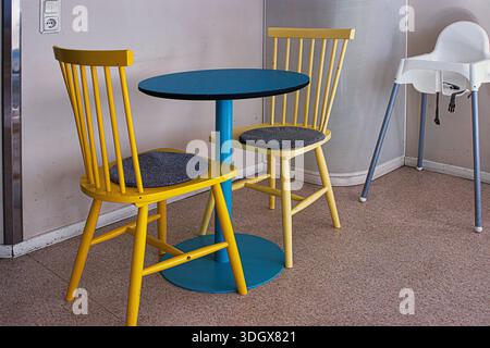 Small dining area with round table two yellow chairs and baby high chair. cozy interior dining corner Stock Photo