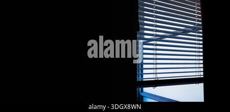 Wide interior banner image of horizontal window blinds with daylight and shadow lines, with large black copy space. Stock Photo