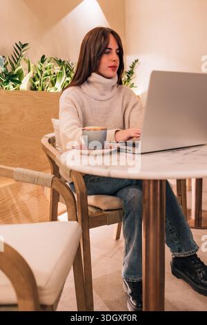 Woman remote working using laptop in cafe Stock Photo